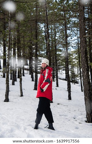 Young happy and beautiful teenage girl dressed in winter clothing standing at snow and smiling. Troodos mountains in Cyprus