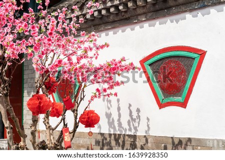 artificial peach blossoms on a branch and decorations in Vintage Historical Chinese House Structure for chinese new year,calligraphy Translation:good bless for new year