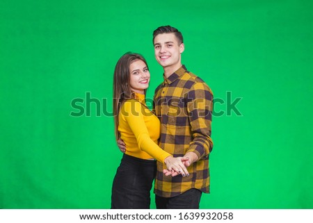 Sweet couple dressed in yellow, dancing slow ballroom dance over green background, during their leisure time.
