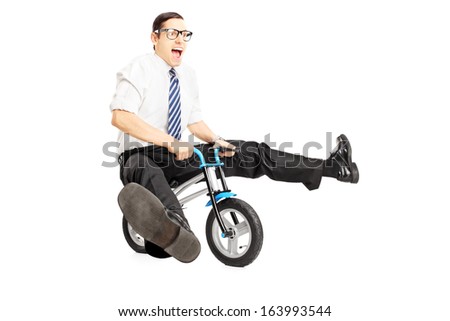 Nerdy young male with tie riding a small bicycle isolated on white background