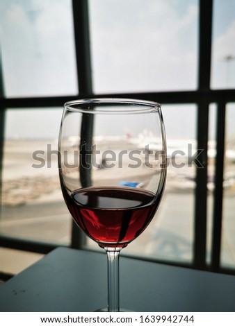 the red wine in a glass on table in the airport lounge with the blur background of the plane at the runway  