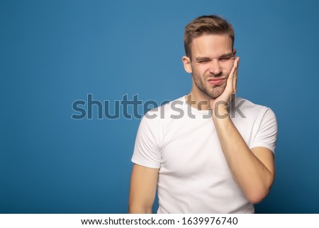 young man suffering from toothache isolated on blue