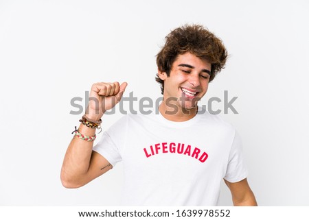 Young caucasian life guard against a white background isolated dancing and having fun.