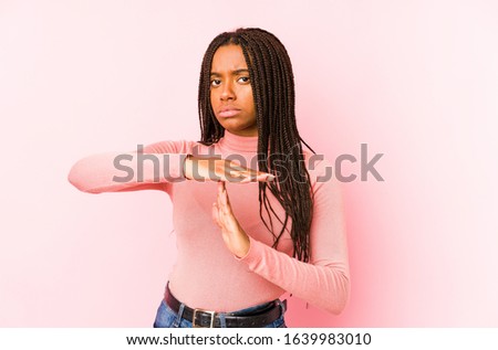 Young african american woman isolated on a pink background showing a timeout gesture.