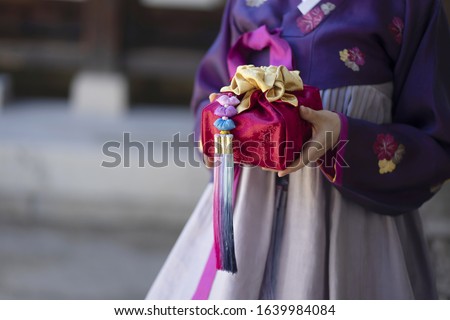 Woman in Korean traditional clothes holding traditional package Royalty-Free Stock Photo #1639984084