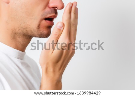 Bad breath. Halitosis concept. Young man checking his breath with his hand. Royalty-Free Stock Photo #1639984429