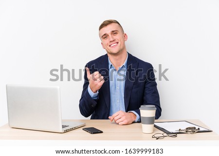 Young business man with a laptop smiling and raising thumb up