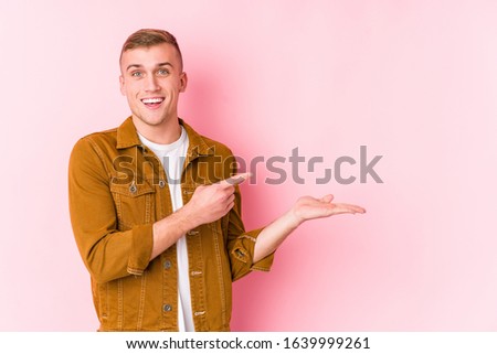 Young caucasian man isolated excited holding a copy space on palm.