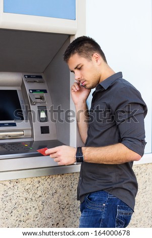 Handsome man talking on the phone and looking at a credit card 