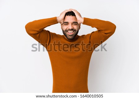 Young latin man against a white background isolated laughs joyfully keeping hands on head. Happiness concept.