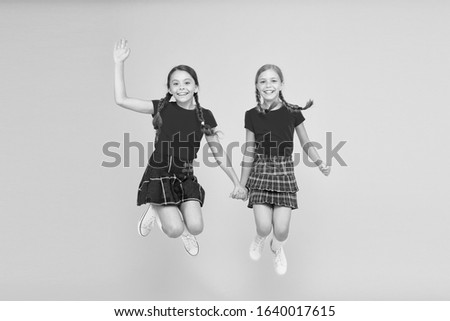 Simply being around. english style fashion. happy little girls in checkered skirt. beauty look. happy children. childhood happiness. trendy school uniform. funny jump. red fashion girls.