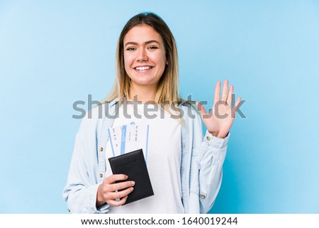 Young caucasian woman holding a passport isolated smiling cheerful showing number five with fingers.