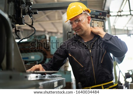 Exhausted factory worker rubs his shoulder due to the back and shoulder aches shows pain expression face, concept working exhaustion, factory worker lifestyle, office syndrome, tiring work hour. Royalty-Free Stock Photo #1640034484