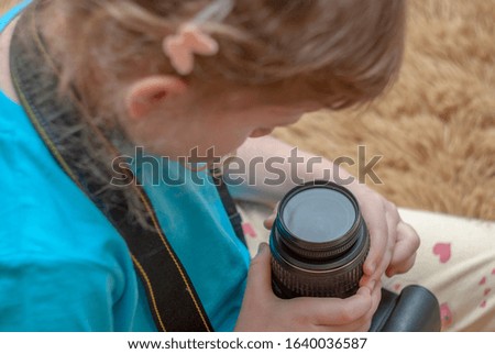 A little girl sits on a sofa and studies a reflex camera.