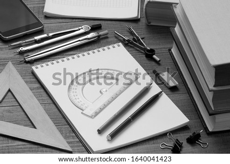 on a wooden table are books, notebooks and drawing instruments for studying mathematics and drawing