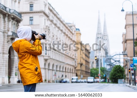 photographer tourist taking picture of city street with votive church on background