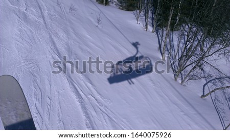 Shadow in the snow of person sitting in the ski lift