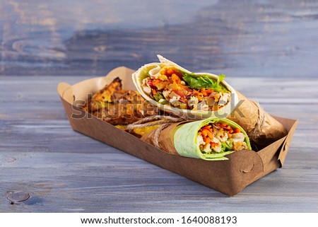 Delicious shawarma sandwich with chicken and potato on wooden background
