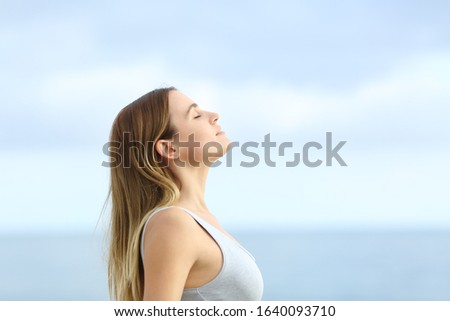 Profile of relaxed girl breathing deeply fresh air on the beach with a blue sky in the background Royalty-Free Stock Photo #1640093710
