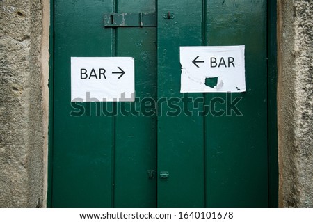 Closed green entrance doors with signs pointing the way to the bar