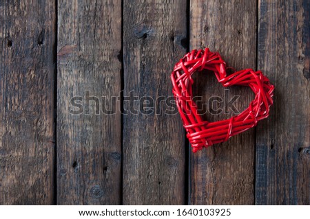 Red wicker heart on a wooden brown background. Love
