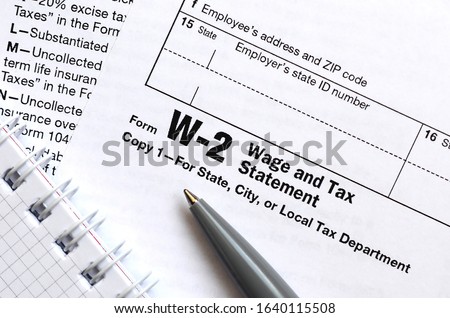 The pen and notebook on the tax form W-2 Wage and Tax Statement. The time to pay taxes Royalty-Free Stock Photo #1640115508