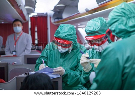 Three people in protective special clothing from viruses and bacteria take tests on Board a plane that arrived from China. Unrecognizable faces. Coronavirus 2019. Threat of epidemic. Out of focus . Royalty-Free Stock Photo #1640129203