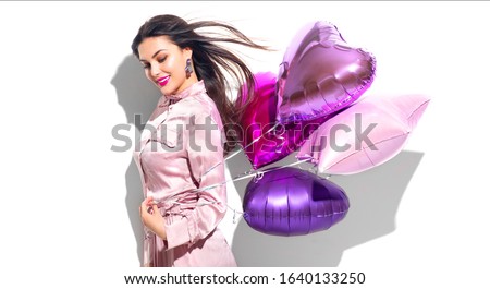 Valentine Beauty girl with colorful heart air balloons laughing, isolated on white background. Beautiful Happy Young woman. Holiday birthday party,  having fun, celebrating with pink color balloon