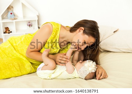 Mother playing with small baby, kissing. indoor