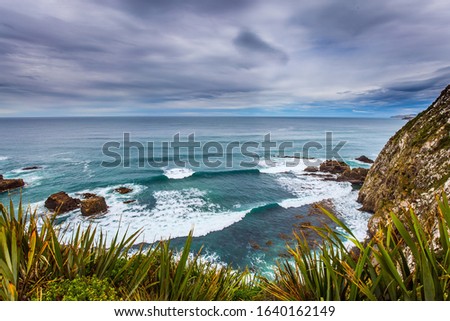  South Island, New Zealand. The picturesque coast of the Pacific Ocean near Cape Nugget. Sunset portends a storm. The concept of active, environmental and photo tourism