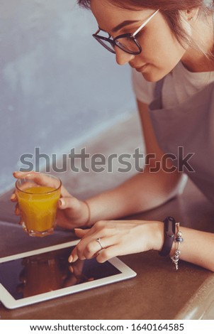 Attractive woman holding a glass of orange juice while standing in the kitchen
