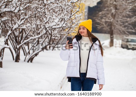 Young beautiful girl with a mobile phone in a winter park