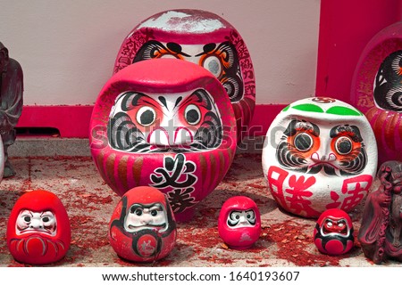 A Daruma doll is a hollow, round, Japanese traditional doll modeled after Bodhidharma, the founder of the Zen tradition of Buddhism. Chinese words mean "must win"