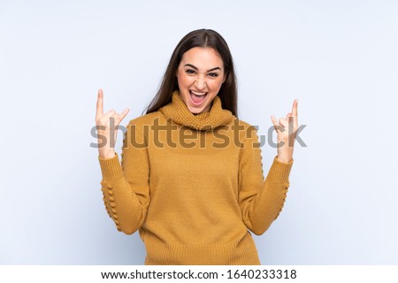 Young caucasian woman isolated on blue background making rock gesture