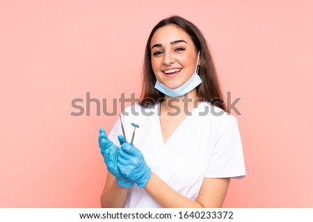 Woman dentist holding tools isolated on pink background applauding Royalty-Free Stock Photo #1640233372