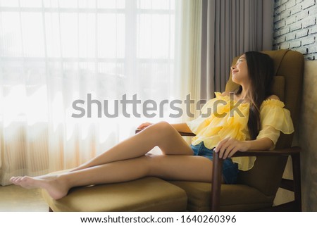 Portrait young asian woman relax happy smile on sofa chair in living room interior