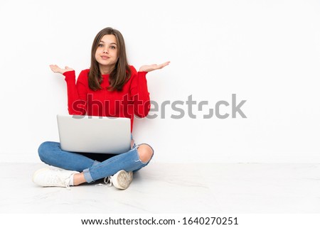 Tenaager girl working with pc isolated on white background having doubts while raising hands