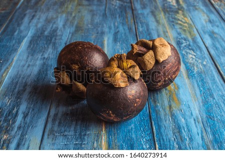 Mangosteen, Three whole fruits fruit on old blue wood table. Shallow depth of field