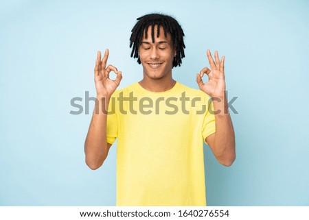 Young african american man isolated on blue background in zen pose