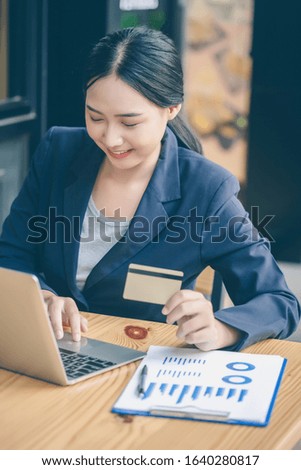 Asian business woman is using credit cards to shop online happily.