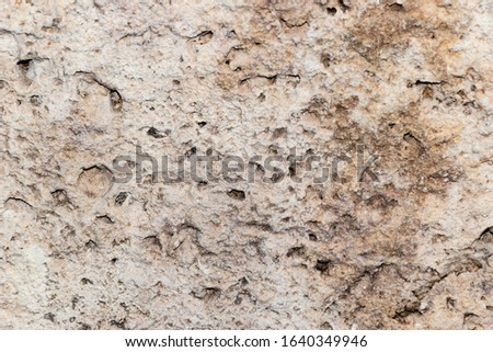 A grunge texture background of an old  stone relief wall with holes