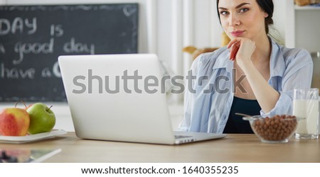 Woman with a cup of coffee and a laptop in the kitchen
