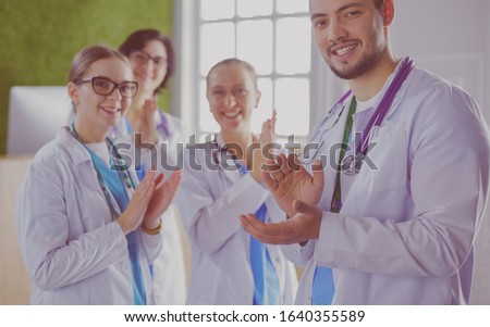 Happy medical team comprising male and female doctors smiling broadly and giving a thumbs up of success and hope