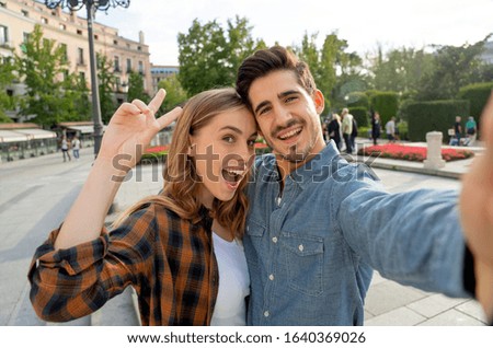 Beautiful friends tourist couple in love taking selfies at sunset while walking and visiting an European city outdoors in a romantic vacation. In Tourism, travel destination and vacation concept.