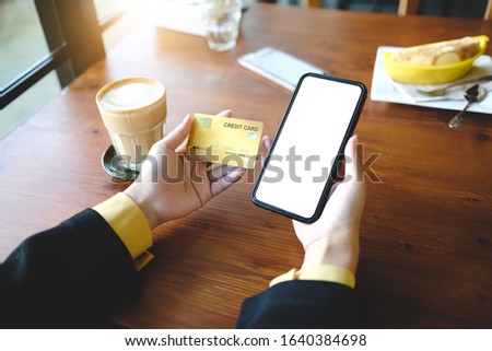 Close up of woman using phone,sending massages phone blank credit card texture within coffee shop.