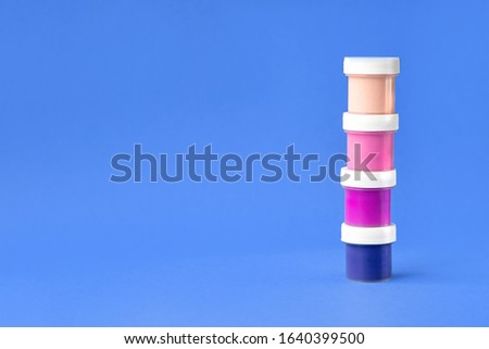 Colorful vibrant cans of gouache paint isolated on color blue background. Painting background. A set of acrylic paints in jars for the artist. Copy space. The concept of creativity and minimalism