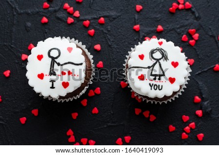 Delicious cupcakes with cute images for Valentine Day on black background. Romantic love background. Happy Valentines Day. Top view.
