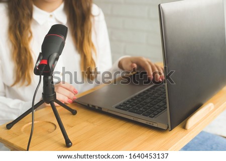 Girl records a podcast with a microphone at home. Modern technologies for creating content for bloggers and influencers.