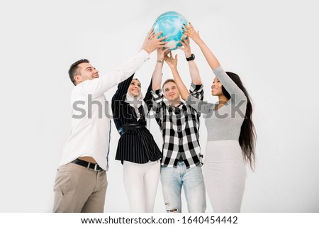 Multiracial group of four young cheerful people holding up the Earth Globe. Young people holding up a globe standing on white background
