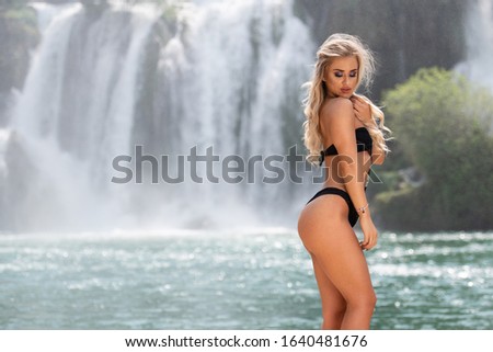 Young Woman Standing Strong in Front of Waterfall And Posing Hear Body